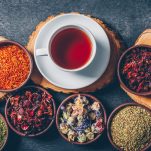 set-wood-stubs-cup-tea-tea-herbs-bowls-dark-textured-background-flat-lay